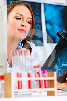 Pensive medical doctor woman looking roentgen photo