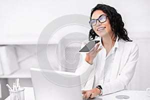 Pensive mexican woman using voice assistant on cellphone