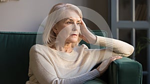 Pensive middle aged lady looking away sit alone at home