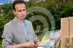 Pensive middle-aged painter holding a palette