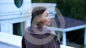 Pensive middle-aged woman standing on balcony of estate, feeling sad and lonely