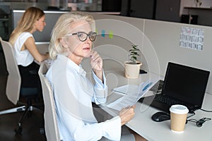 Pensive middle-aged woman thinking distracted from office work