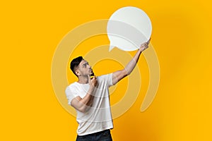 Pensive middle eastern man holding blank speech bubble on yellow