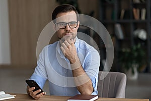 Pensive millennial handsome businessman dreaming in office.