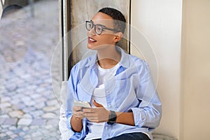 Pensive millennial latina lady in glasses, enjoy chat on mobile phone with smartwatch