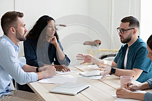 Pensive mixed race teammates discussing project details.