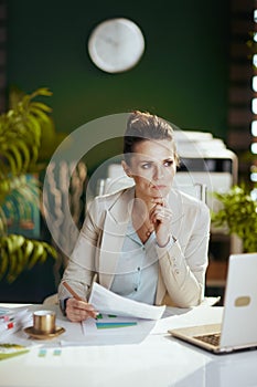 pensive modern accountant woman in modern green office