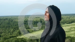 Pensive Muslim woman in black headscarf admiring nature landscape breathing freedom closeup slowmo