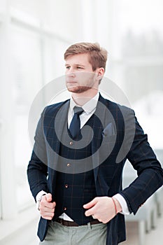 Pensive newcomer businessman in a business suit stands near a wi