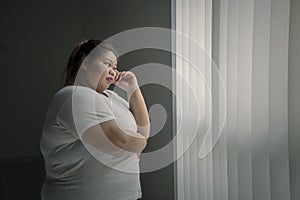 Pensive obese woman looking out the window