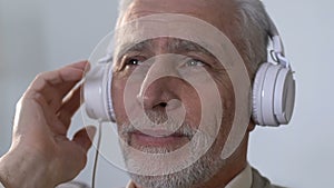 Pensive old man in headphones listening to music, remembering youth, nostalgia