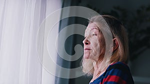 Pensive old woman thinking near the big window. Mental health and lonelines during covid outbreak