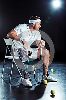 pensive paralympic tennis player with tennis racket looking away while resting