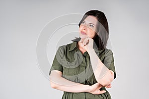 Pensive plus size model in casual clothes, fat woman on gray background, overweight female body