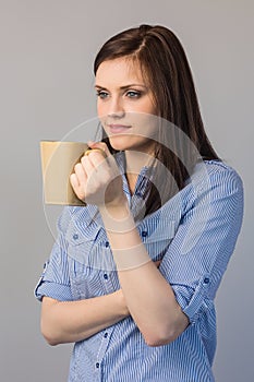 Pensive pretty brunette holding cup of coffee