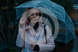 Pretty girl holding umbrella and strolling on rainy autumn day. photo looks like film frame or movie screenshot