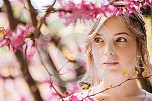 Pensive pretty young woman in spring garden