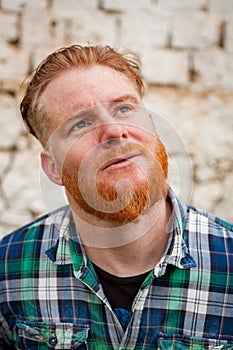 Pensive red haired hipster man with blue plaid shirt