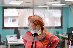 Pensive redhead woman gazing out in office.