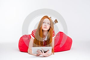 Pensive redhead young woman using tablet