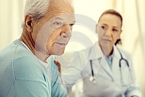 Pensive retired man looking upset during medical consultation