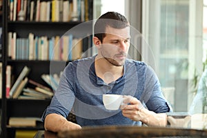 Pensive sad man looks away in a coffee shop photo