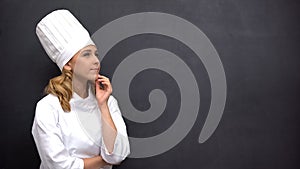 Pensive senior cook touching chin against black board, searching for inspiration