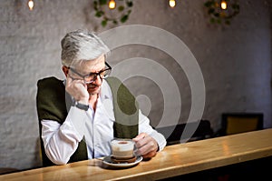 Pensive senior having a coffee in the bar