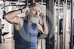 Pensive senior male is listening to music in athletic center