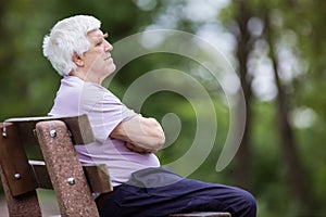 Pensive senior man sitting on bench in park