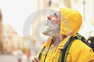 Pensive senior man walking in city while raining