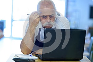 pensive senior man working on laptop