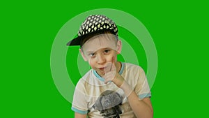 Pensive serious Caucasian preschool boy in a cap looks at the camera. Chroma key