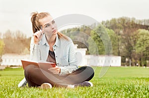 Pensive serious woman sitting outside and writing in her diary