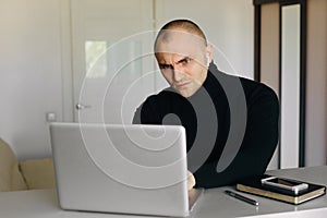 Pensive short haired man sitting at tablework at laptop thinking of problem solution, thoughtful male employee pondering