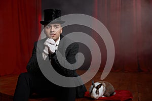 Pensive showman in suit sitting on theatre stage resting after magic show