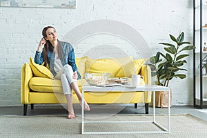 pensive smiling girl sitting on sofa and looking away