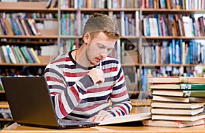 Pensive student with laptop studying in the university library