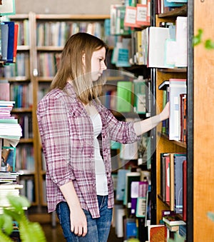 Pensive student in the library surrounded by books