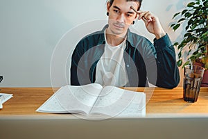 Pensive student making notes from laptop