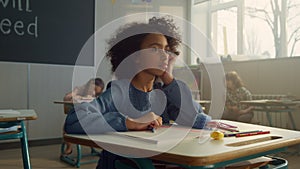 Pensive student sitting at school desk in class. Female pupil learning science