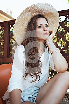 Pensive stylish housewife in white shirt with hat