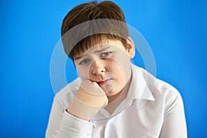 Pensive teenage boy on blue background