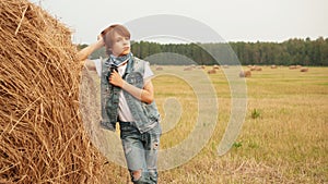 Pensive teenage boy leaning at haystack in field