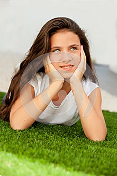 Pensive teenager girl lying on the grass