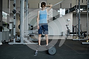 Pensive teenager nerd choosing between heavy and light dumbbells