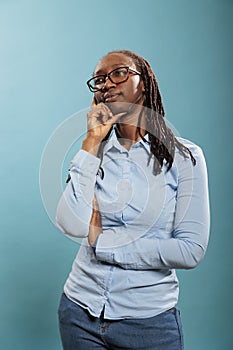 Pensive thoughtful african american woman being meditative and introspective on blue background.