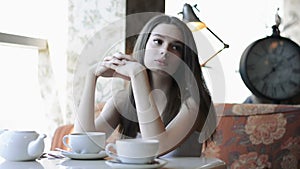 Pensive, thoughtful beautiful woman drinking coffee in cafe