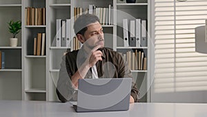 Pensive thoughtful Caucasian man work with laptop in office male writer journalist web designer employee businessman