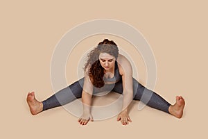 Pensive thoughtful close eyes outsize obesity woman with superfluous weight, doing stretching hands on floor, split legs